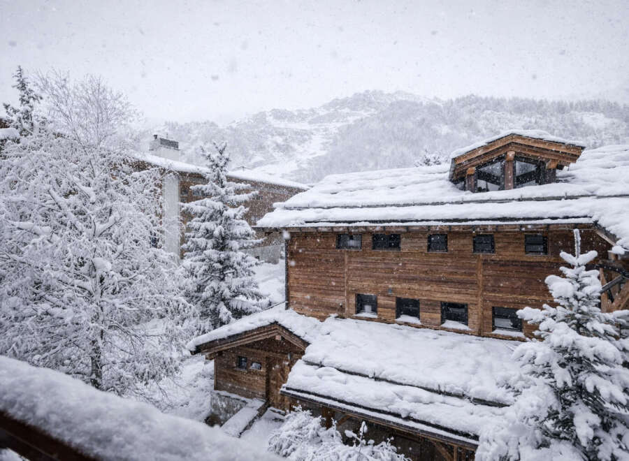 Nestled in a snowy landscape, this stunning property showcases a charming wooden exterior and a cozy atmosphere.
