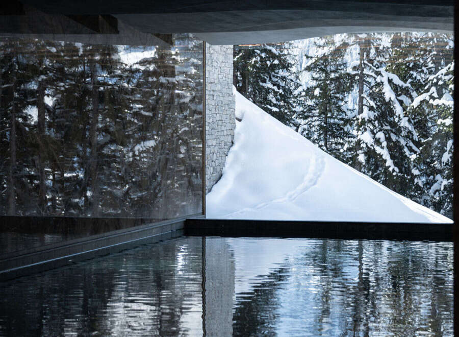 Experience luxury living with this stunning property featuring a serene pool and breathtaking views of a snow-covered landscape.