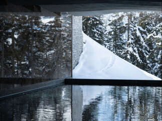 Experience luxury living with this stunning property featuring a serene pool and breathtaking views of a snow-covered landscape.
