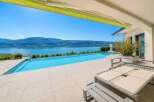 Experience luxury living with this stunning infinity pool overlooking a serene lake and majestic mountains.