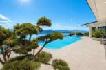 Experience luxury living with this stunning infinity pool overlooking a serene lake and majestic mountains.