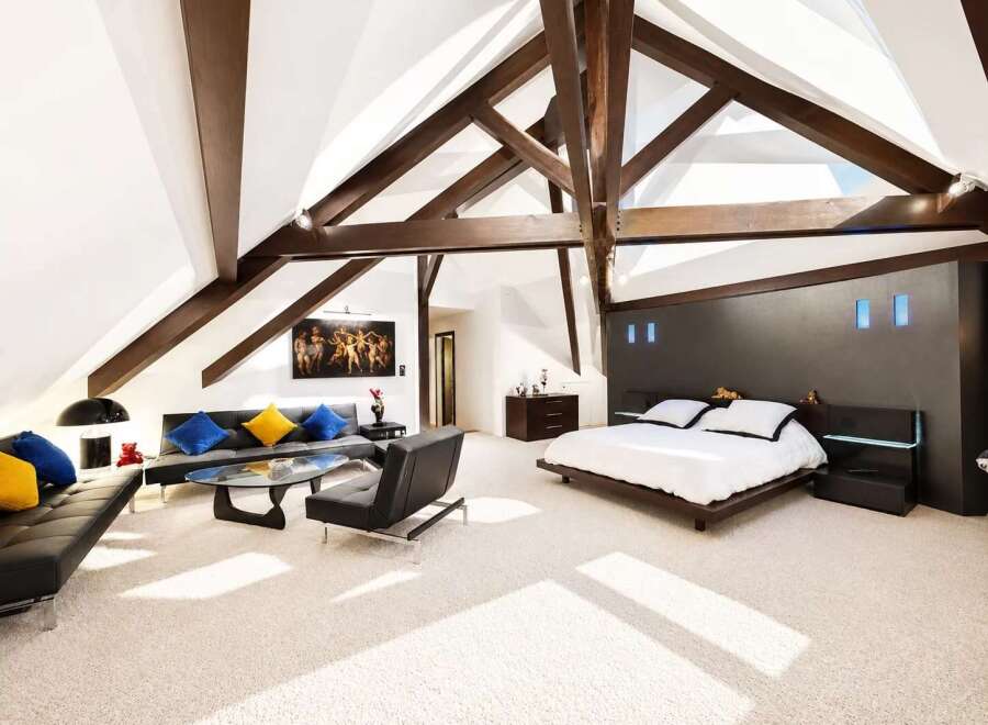 Experience luxury living in this stunning attic bedroom featuring a spacious king-size bed with a modern dark wood headboard and integrated lighting.