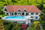 Experience luxury living in this stunning modern villa, featuring a breathtaking infinity pool overlooking lush green hills.