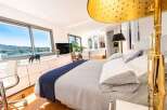Experience luxury living in this stunning bedroom featuring expansive windows with breathtaking water views.