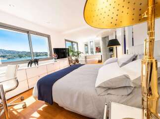 Experience luxury living in this stunning bedroom featuring expansive windows with breathtaking water views.