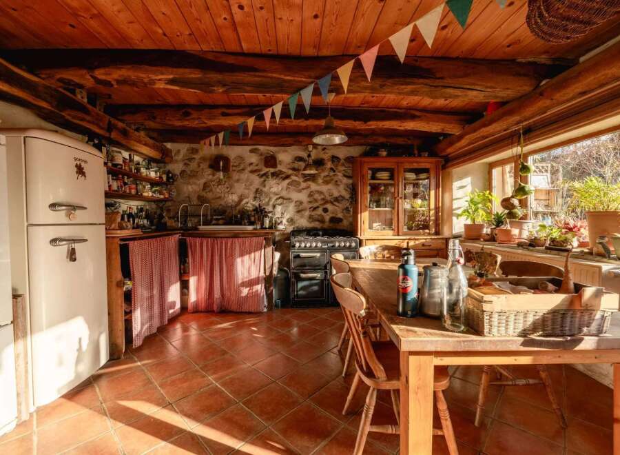 Rustic kitchen with exposed wooden beams and terracotta tile floors.