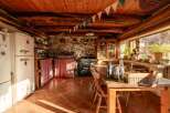Rustic kitchen with exposed wooden beams and terracotta tile floors.