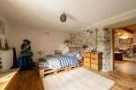 Rustic bedroom with pallet bed and stone wall.