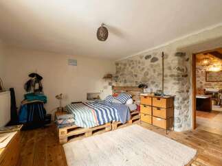 Rustic bedroom with pallet bed and stone wall.