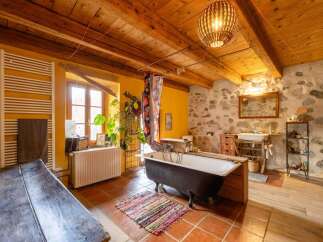 Rustic bathroom with exposed wooden beams, terracotta tile flooring, and a clawfoot bathtub.