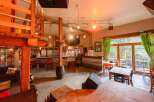 Rustic-chic bar with a spacious layout, featuring a wooden loft, large windows overlooking a patio, and ample seating.