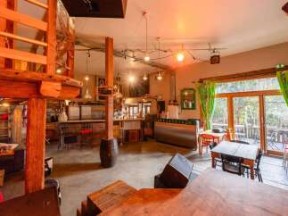 Rustic-chic bar with a spacious layout, featuring a wooden loft, large windows overlooking a patio, and ample seating.