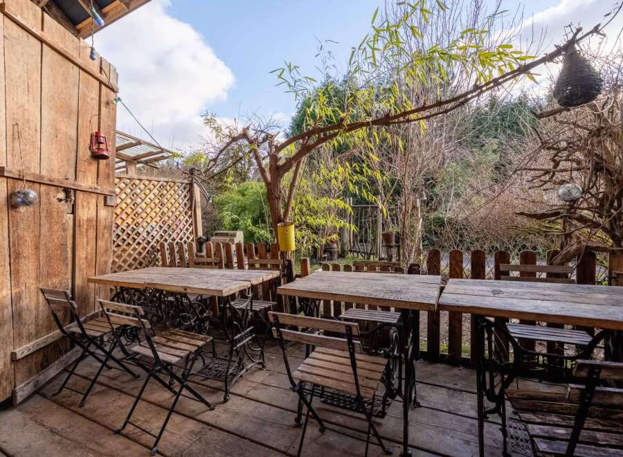 Enjoy al fresco dining on this charming patio, featuring rustic wooden tables and chairs repurposed from vintage sewing machines.