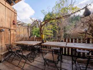 Enjoy al fresco dining on this charming patio, featuring rustic wooden tables and chairs repurposed from vintage sewing machines.