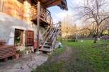 Rustic wooden staircase leading to a charming wooden balcony, nestled against a stone building.