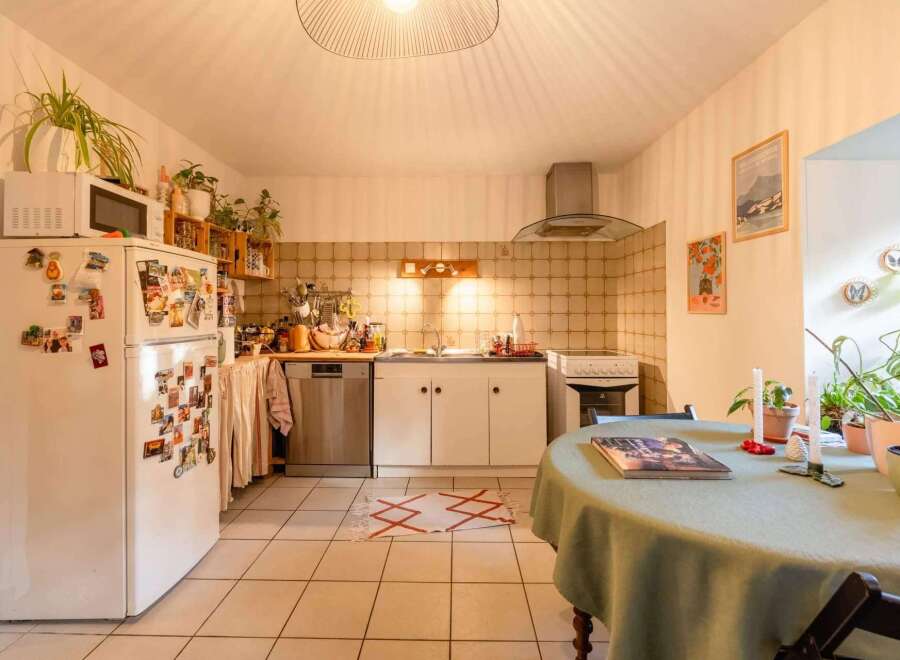 Charming kitchen with tiled floors and walls, featuring white cabinets and appliances.