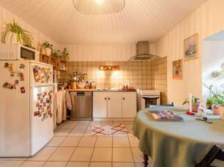 Charming kitchen with tiled floors and walls, featuring white cabinets and appliances.