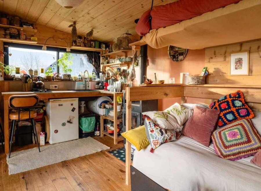 Cozy tiny home with a lofted bed, full kitchen, and wood-burning stove.