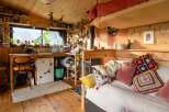 Cozy tiny home with a lofted bed, full kitchen, and wood-burning stove.