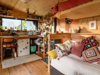 Cozy tiny home with a lofted bed, full kitchen, and wood-burning stove.