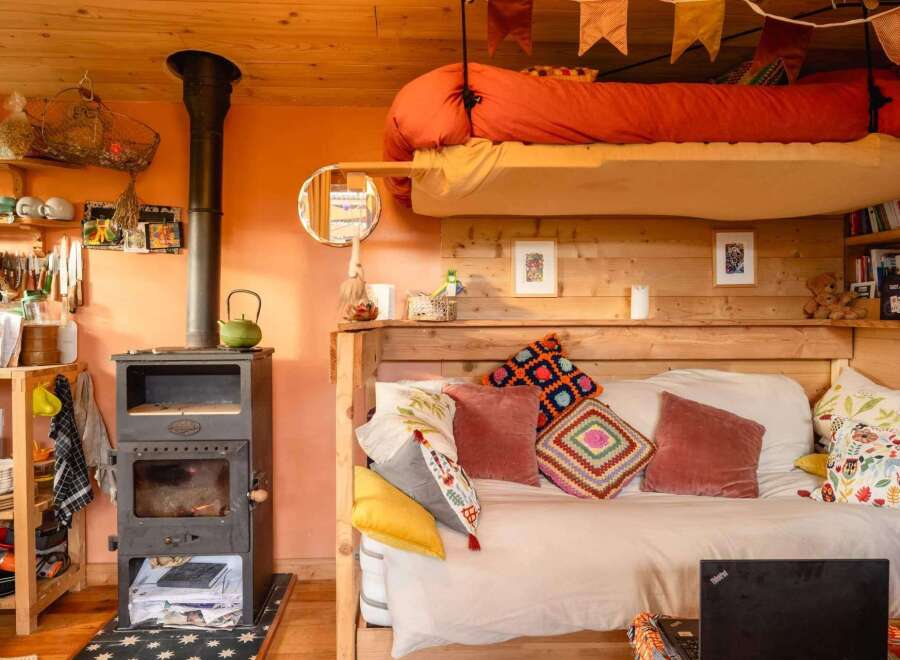 Cozy tiny home with a lofted bed, wood-burning stove, and built-in daybed.