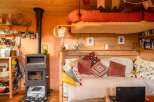 Cozy tiny home with a lofted bed, wood-burning stove, and built-in daybed.