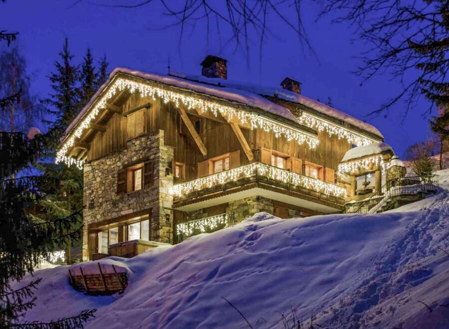 Luxury chalet in the French Alps, adorned with twinkling lights for a magical winter escape.
