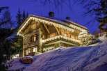 Luxury chalet in the French Alps, adorned with twinkling lights for a magical winter escape.