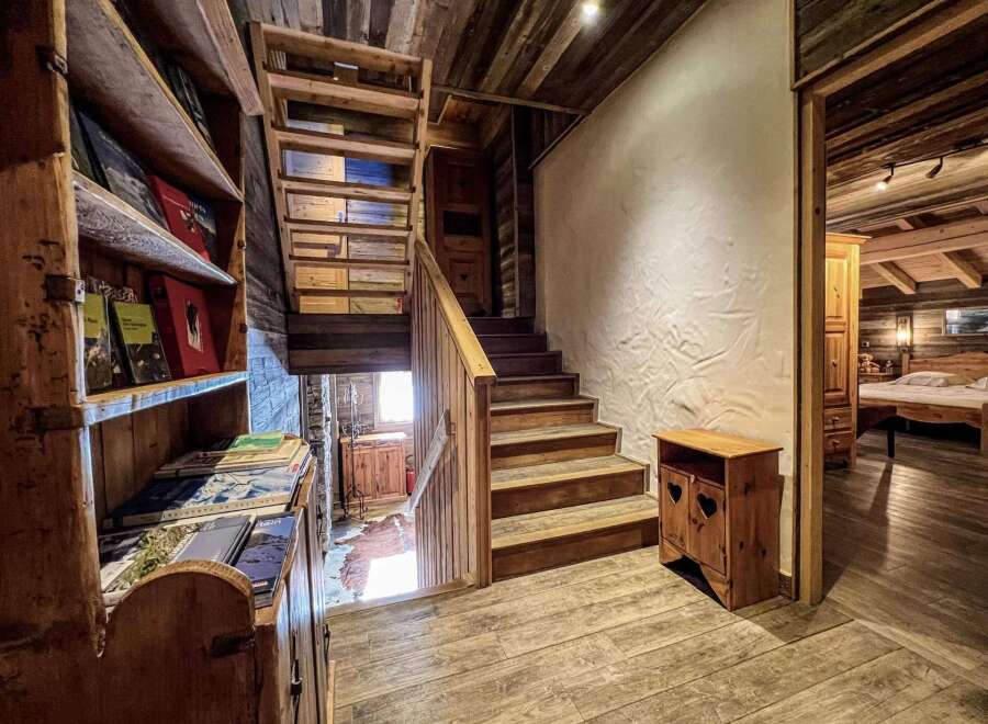 Rustic wooden chalet with charming wooden staircase and built-in bookshelf.