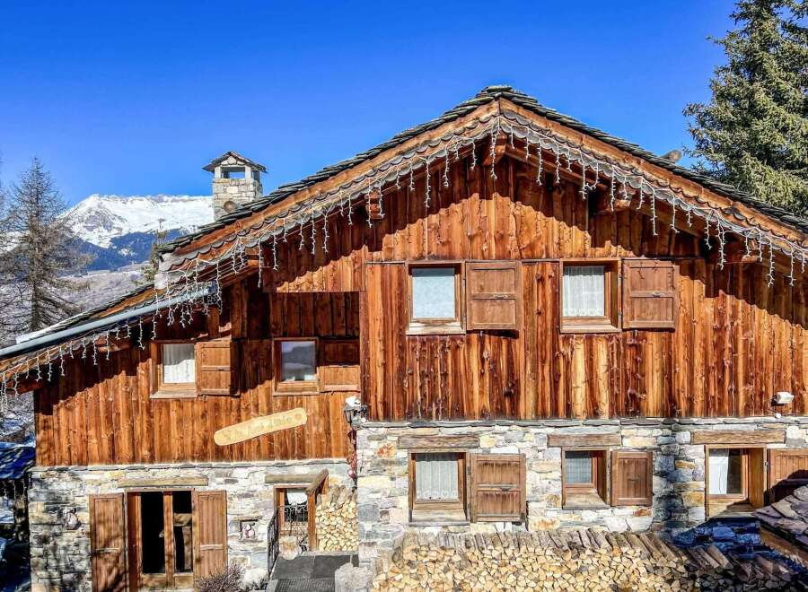 This charming chalet boasts a rustic wooden exterior with stone accents, creating a cozy and inviting atmosphere.