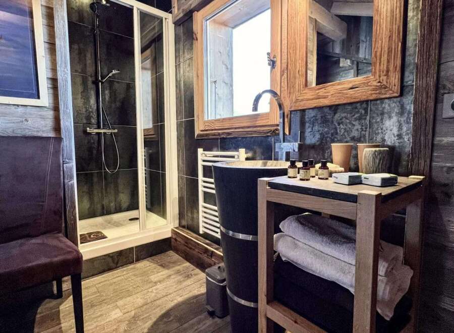 Luxury chalet bathroom boasts a spacious shower, stylish wooden vanity, and plush towels.
