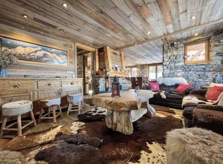 This stunning chalet boasts a rustic-chic interior with exposed wood beams, a stone fireplace, and luxurious cowhide rugs.