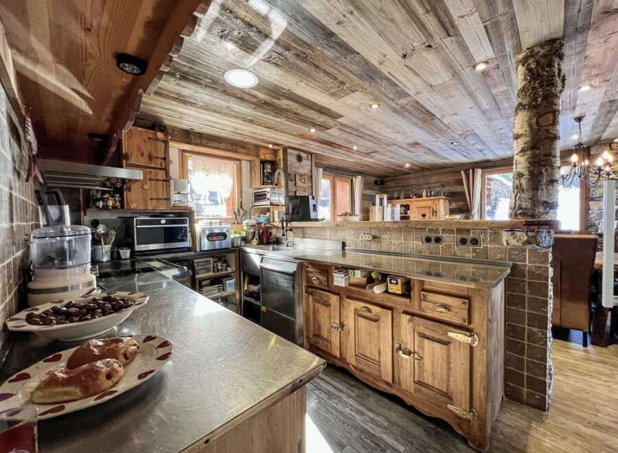 Rustic mountain kitchen with wood-paneled ceiling and stainless steel countertops.