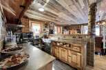 Rustic mountain kitchen with wood-paneled ceiling and stainless steel countertops.