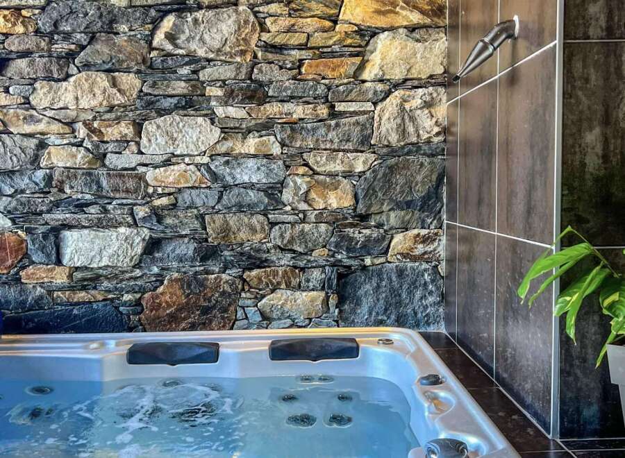 Indulge in ultimate relaxation in this luxurious hot tub, nestled against a stunning stone wall.