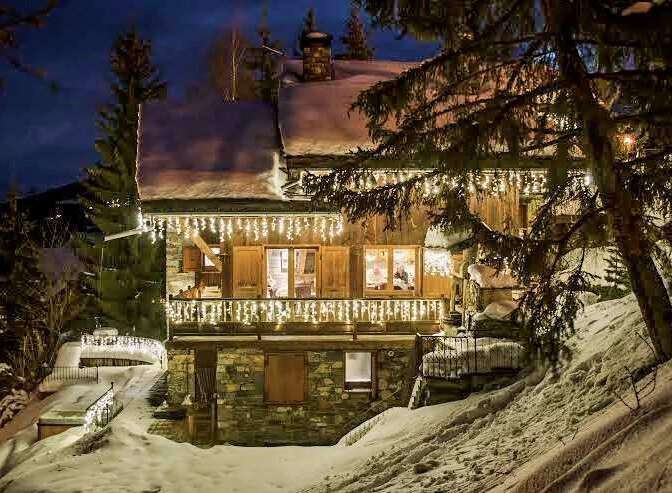 Luxury chalet nestled in a snowy mountainside, adorned with enchanting Christmas lights.