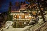 Luxury chalet nestled in a snowy mountainside, adorned with enchanting Christmas lights.