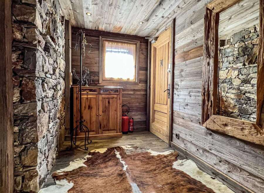 This stunning chalet boasts a rustic-chic entryway, featuring a captivating blend of reclaimed wood and natural stone.