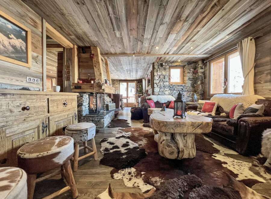 Rustic mountain chalet with wood-paneled ceilings, stone fireplace, and cozy furnishings.