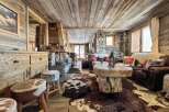Rustic mountain chalet with wood-paneled ceilings, stone fireplace, and cozy furnishings.