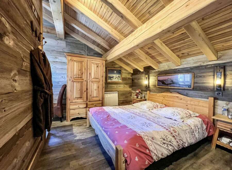 Cozy chalet bedroom with wooden beams, rustic decor, and a comfortable double bed.