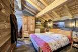 Cozy chalet bedroom with wooden beams, rustic decor, and a comfortable double bed.