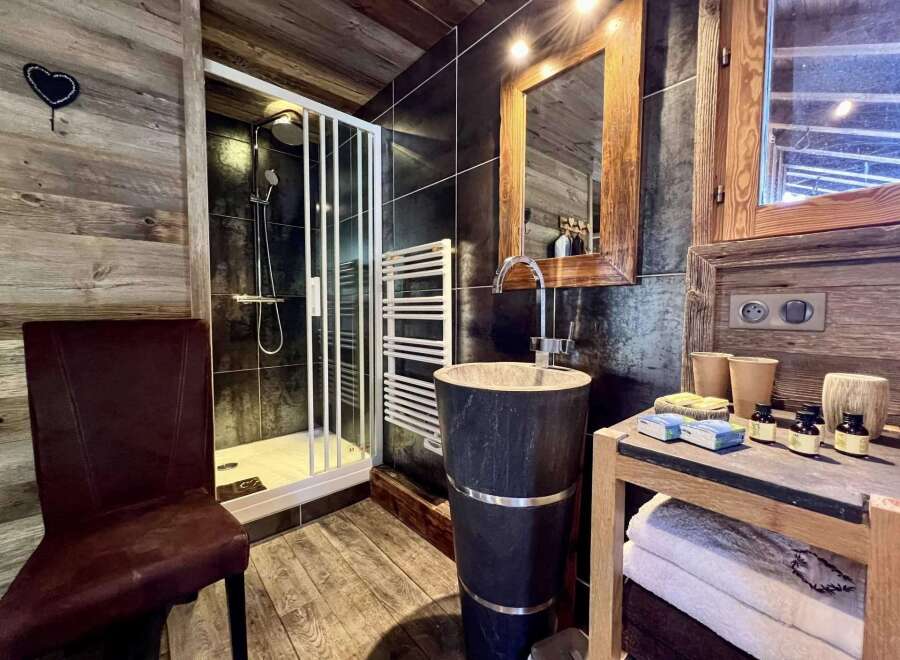 Rustic-chic bathroom with a walk-in shower, stylish stone sink, and wooden accents.