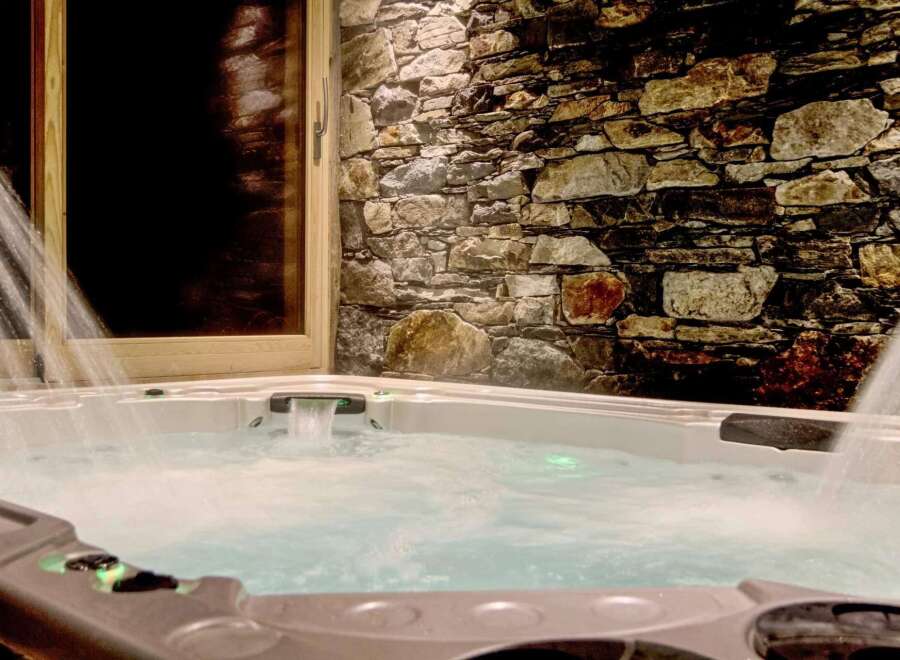 Luxury chalet with a private hot tub nestled against a stunning stone wall.