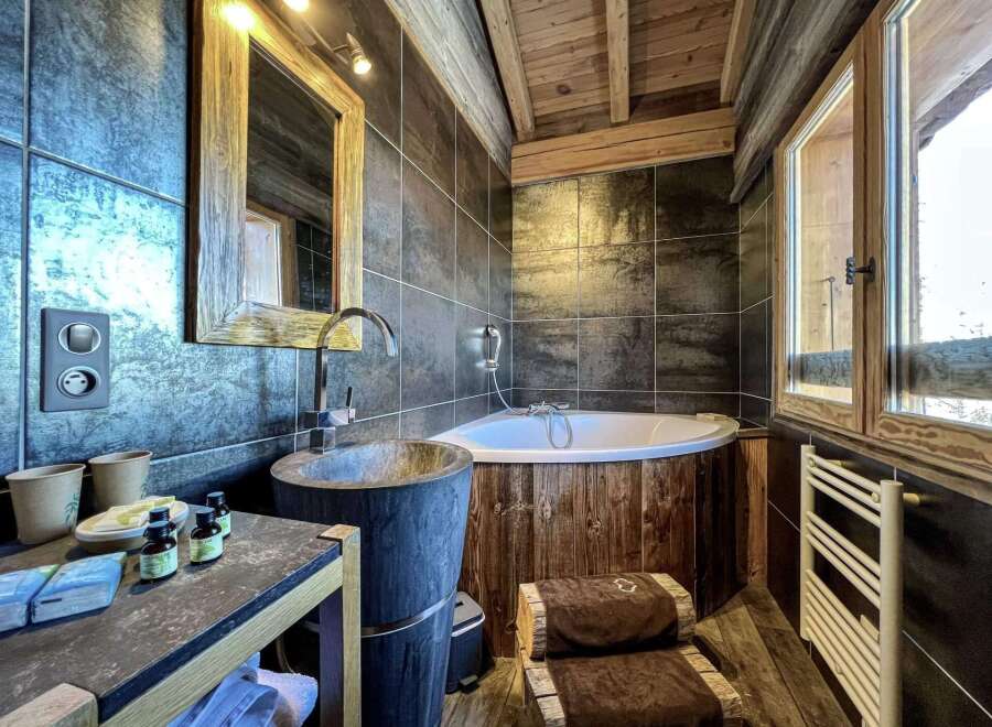 Luxurious bathroom with a rustic wooden bathtub and a modern stone sink.