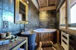 Luxurious bathroom with a rustic wooden bathtub and a modern stone sink.