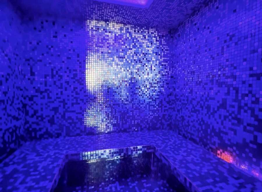 Indulge in tranquility within this stunning steam room, featuring a captivating mosaic tile design and soothing purple LED lighting.