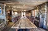 This stunning chalet boasts a magnificent, rustic dining table perfect for large gatherings, surrounded by comfortable leather chairs.