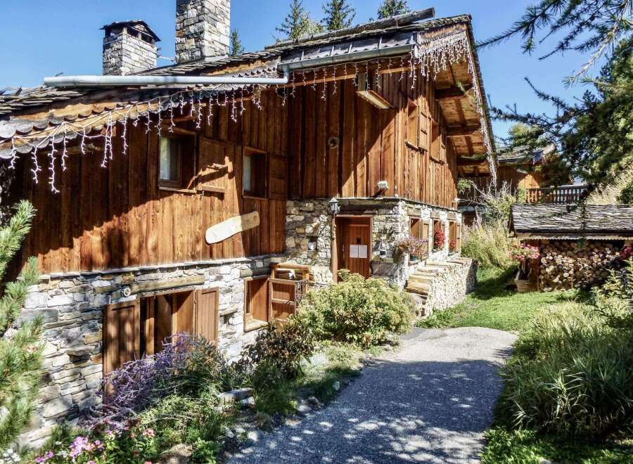 This charming chalet boasts a rustic wooden exterior with stone accents, creating a cozy and inviting atmosphere.