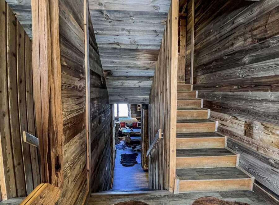 Rustic mountain home with stunning wood-paneled staircase and cozy cowhide rugs.
